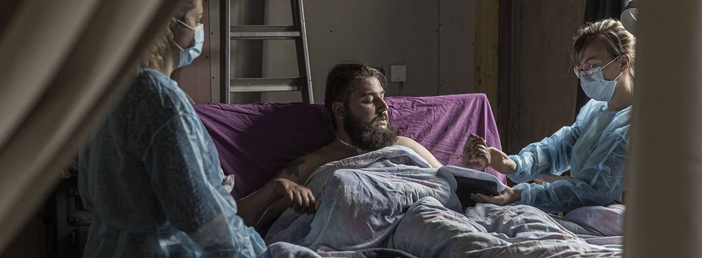 Soignantes entourent patient sur son lit